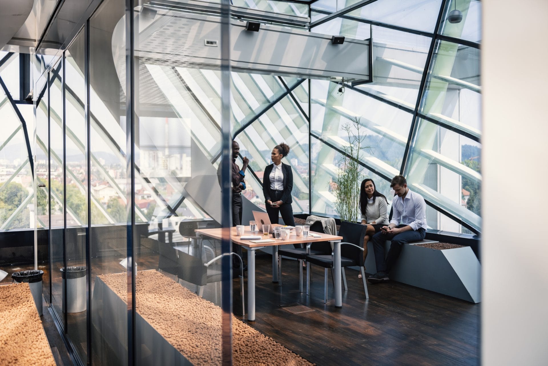 Glass-walled conference room with people meeting around a table